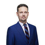 A man with short, neatly groomed dark hair, trimmed beard and moustache.